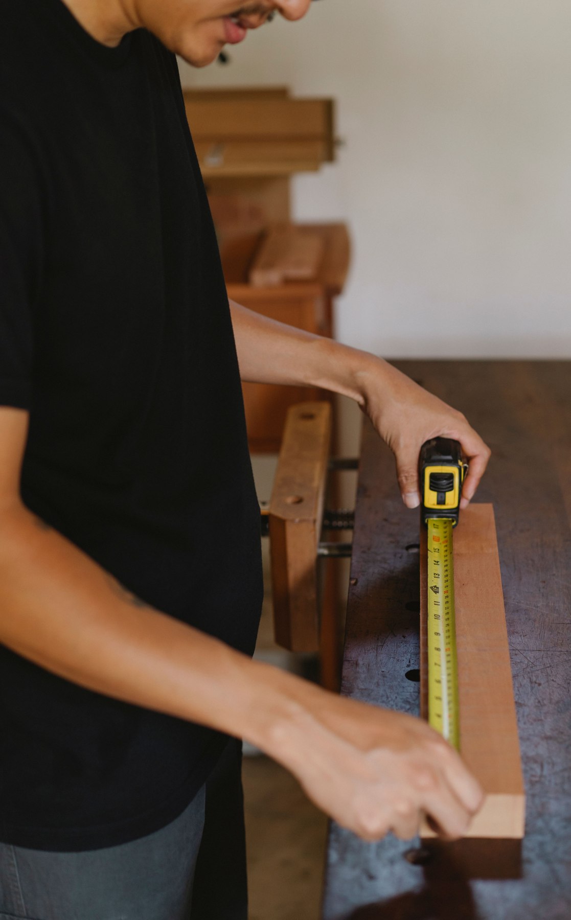 A woodworker measuring a board at a workbench